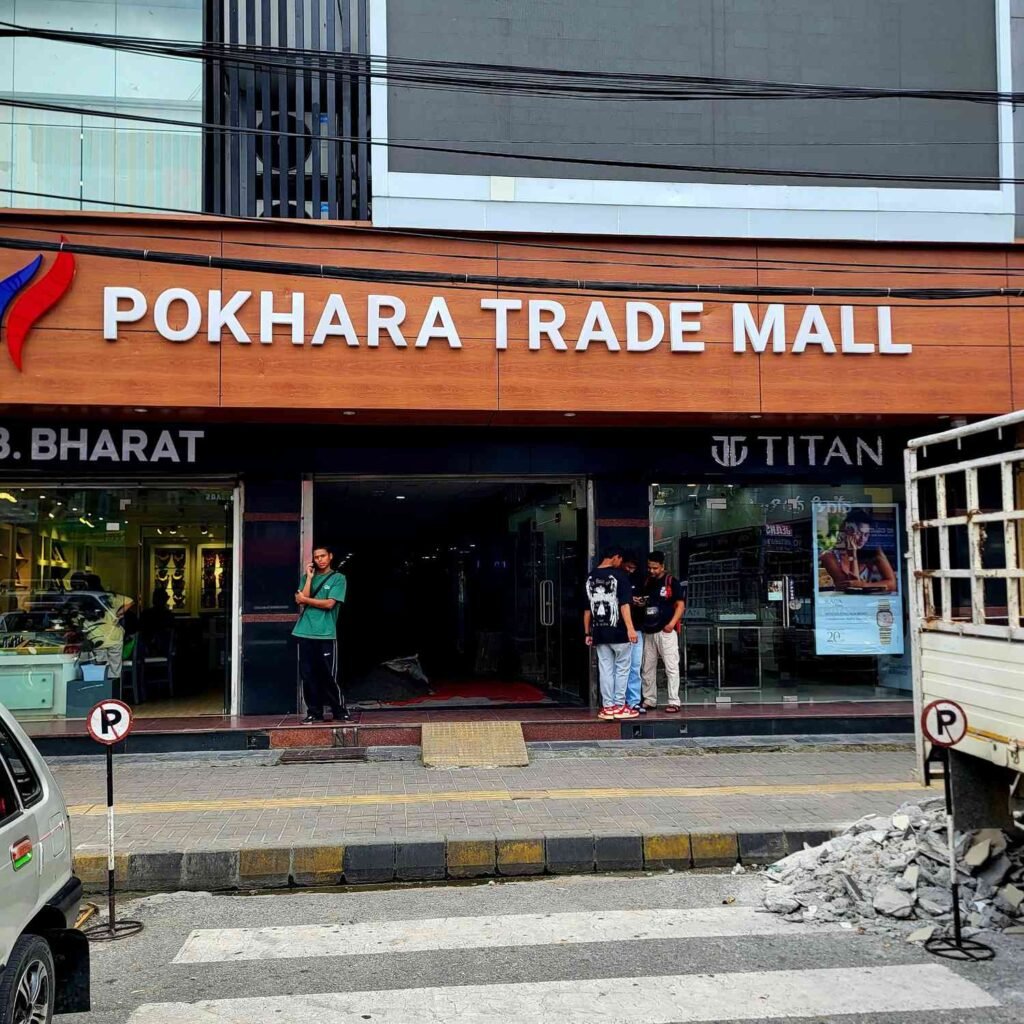 A street-level perspective looking directly at the main entrance doors of Pokhara Trade Mall
